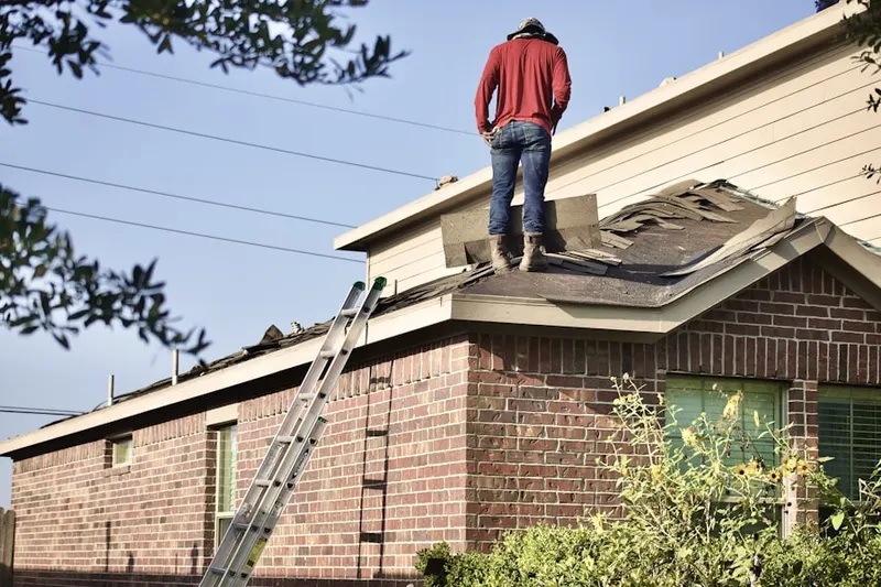 Professional roofer working on a residential roof in Flora